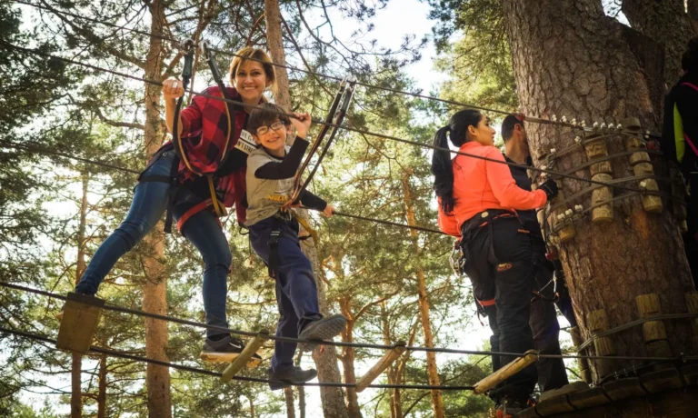 Mensen op een touwparcours hoog tussen de bomen in een klimbos