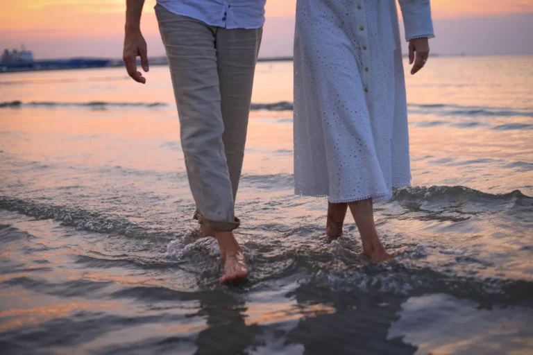 Stel wandelt hand in hand over het strand bij zonsondergang