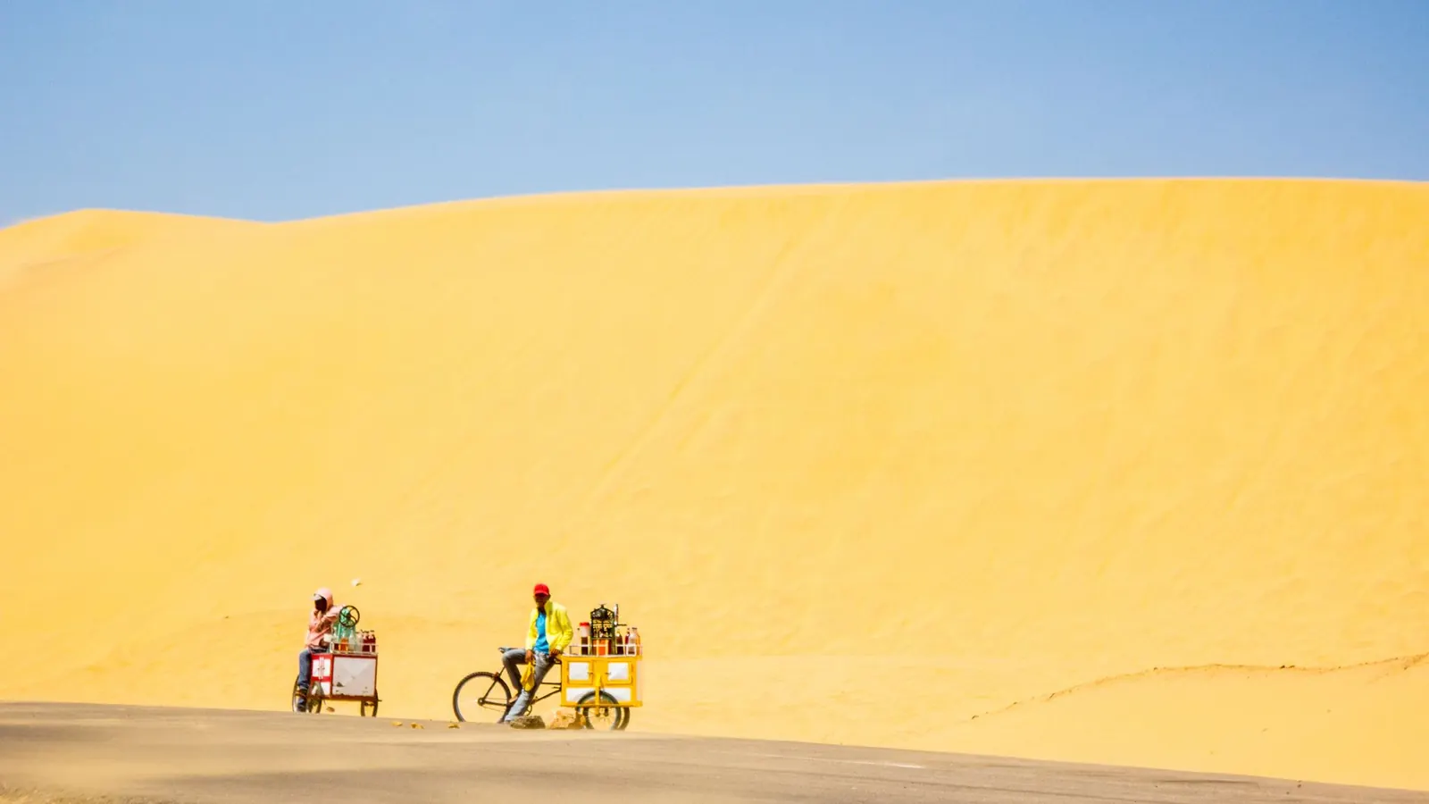 Twee volwassenen fietsen samen door de duinen op een zonnige dag