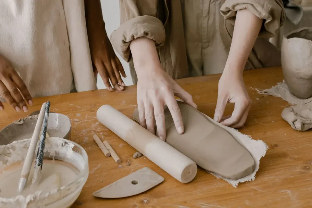 Handen van een volwassene vormen klei tijdens een pottenbakworkshop