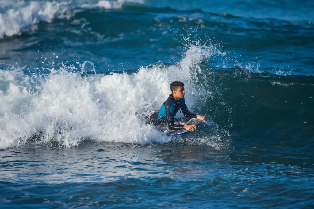 Tiener met surfplank loopt de zee in tijdens een surfles