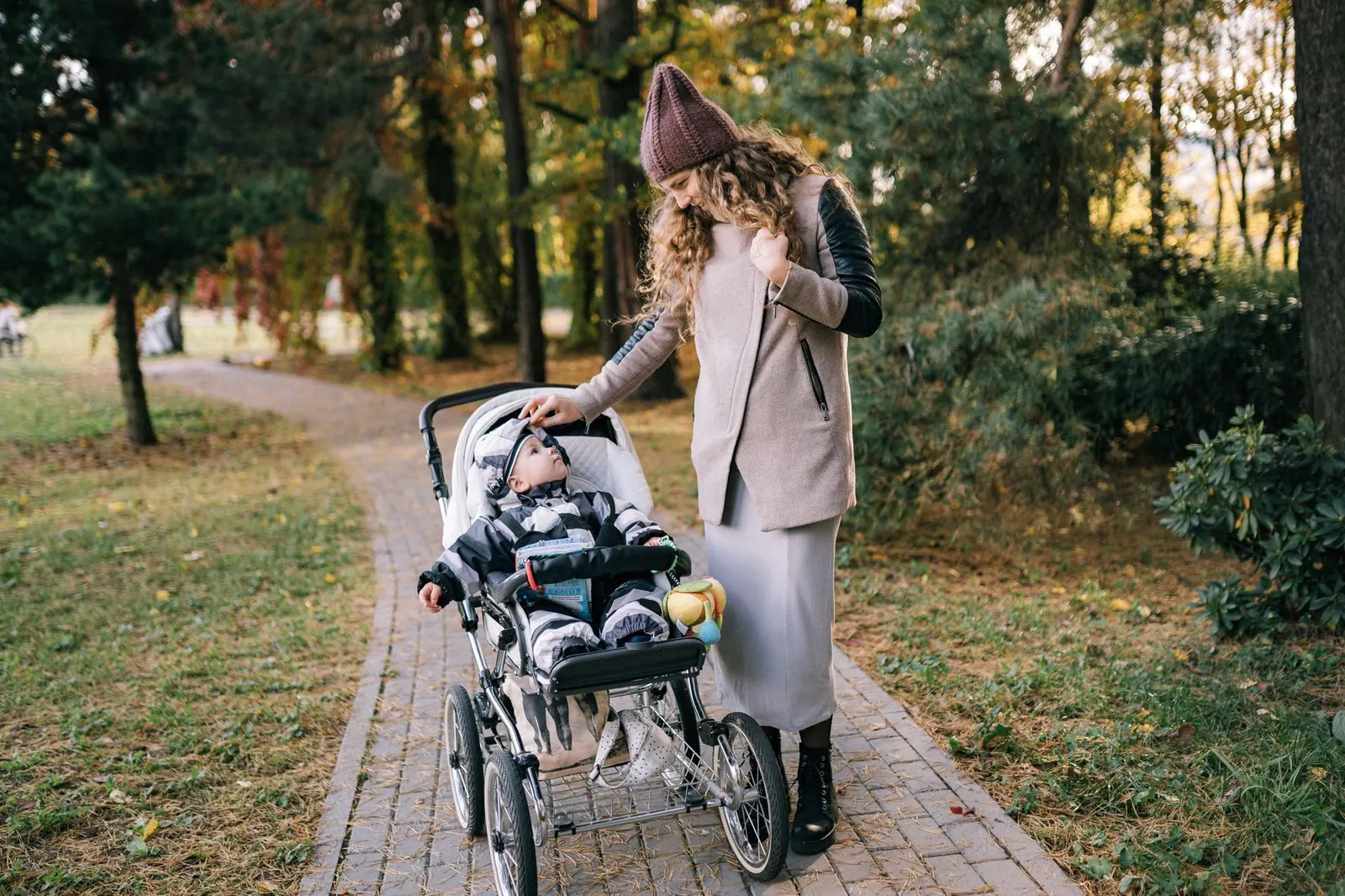 Ouders wandelen met een kinderwagen door een park in de herfst